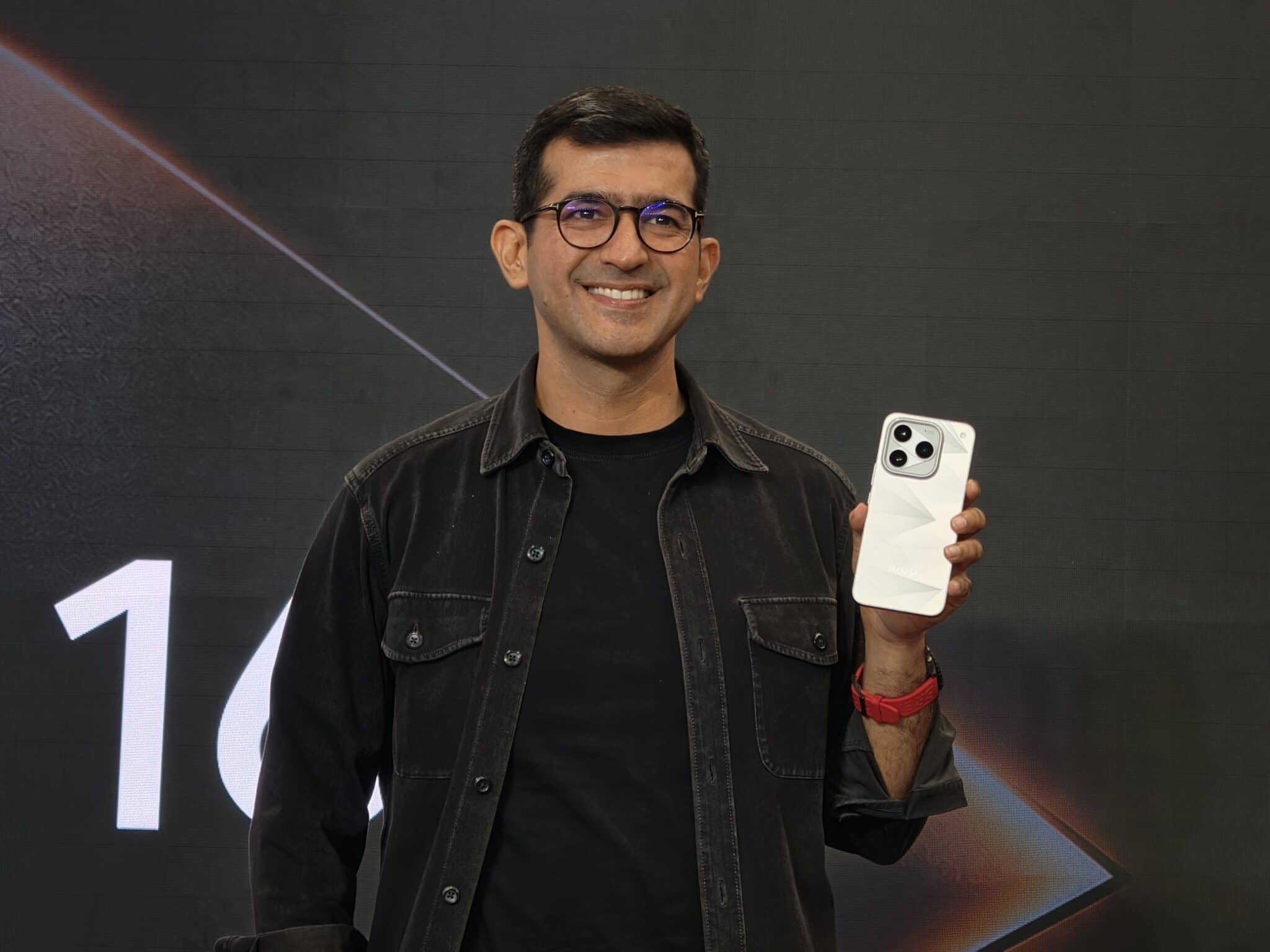 iQOO executive holding a white iQOO smartphone at launch event